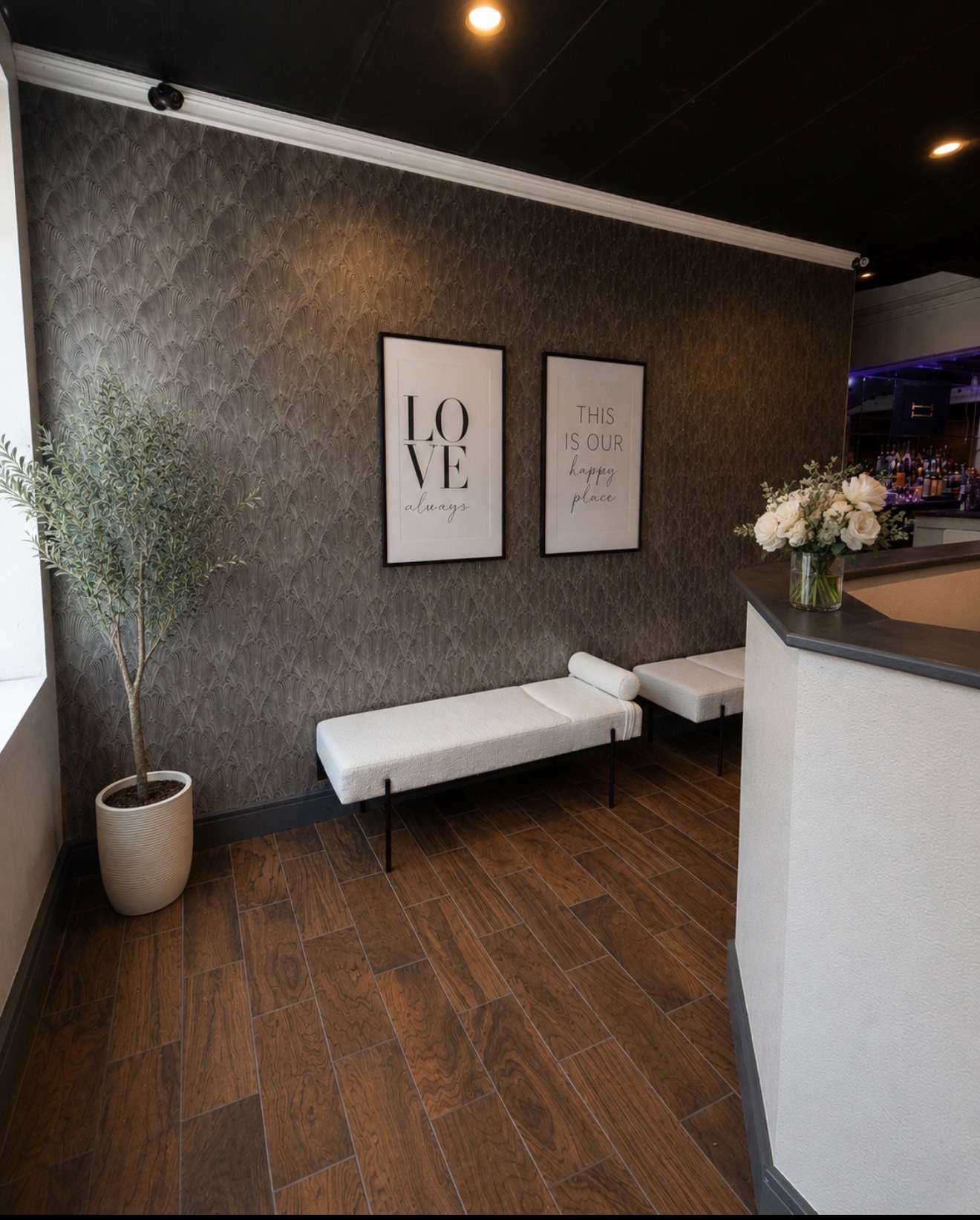Entry vignette with 'Love Always' and 'This Is Our Happy Place' framed prints, olive tree, and white bench seating