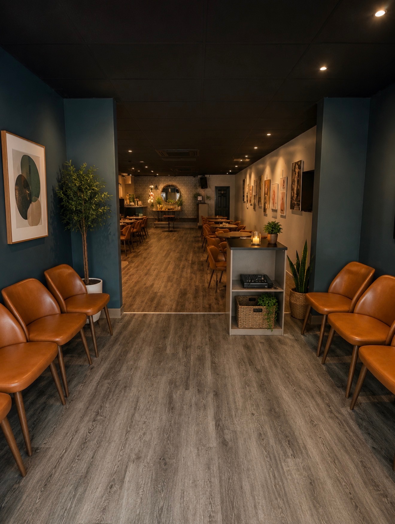 Lounge and entry corridor with moody blue walls, gallery art, and tan leather seating