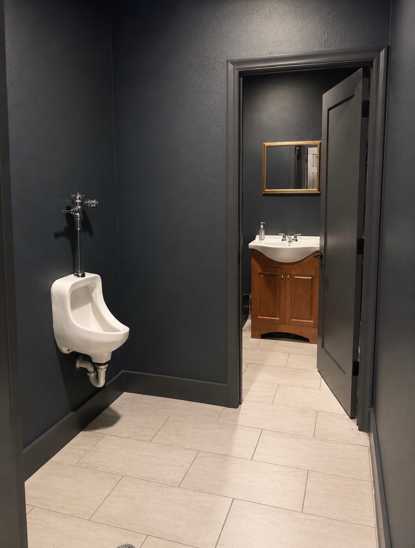 Second restroom with dark walls, marble tile, and gold-framed mirror