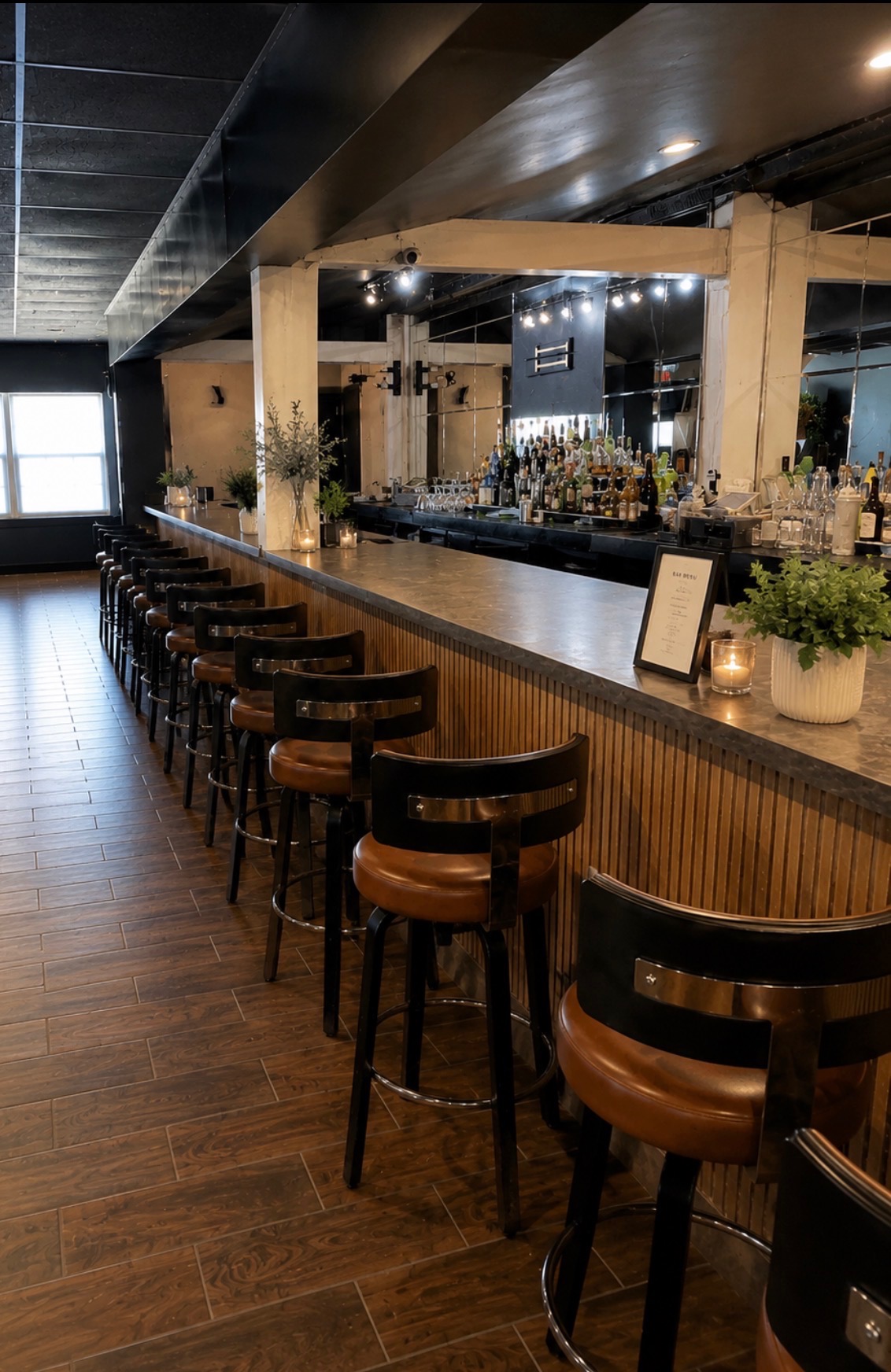 Full-service bar with wood paneling, mirrored back bar, and leather swivel stools